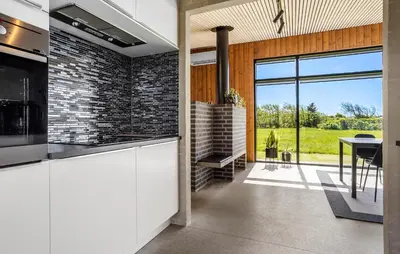 a kitchen with white cabinets and a brick wall at Two-Bedroom Holiday Home In Vinderup in Vinderup