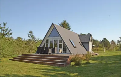 a small house with a pitched roof on a field at Two-Bedroom Holiday Home In Logstor in Løgstør