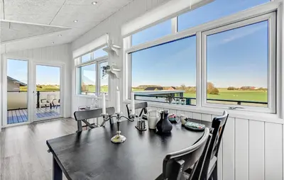 a dining room with a table and chairs and windows at Two-Bedroom Holiday Home In Lemvig in Lemvig