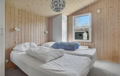 two beds in a room with wooden walls and a window at Cozy Home In Roslev With Wifi in Roslev
