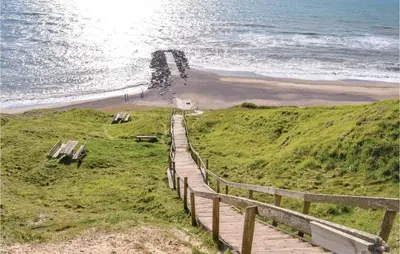 a wooden boardwalk leading to a beach with the ocean at Two-Bedroom Apartment In Lemvig in Lemvig