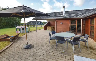 a patio with a table and chairs and an umbrella at Three-Bedroom Holiday Home In Vinderup in Vinderup
