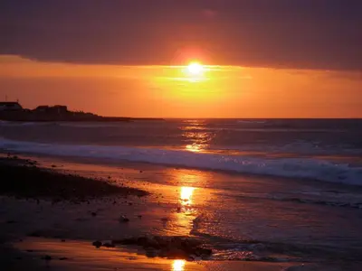 a sunset on a beach with the ocean at Klitmøller Hotel in Klitmøller
