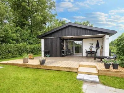 a small house with a wooden deck in a yard at 5 person holiday home in Vinderup-By Traum in Vinderup