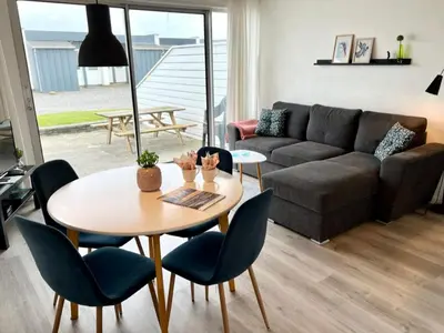a living room with a table and chairs and a couch at Agger Tange Feriecenter lejligheder - 100 m fra Vesterhavet in Vestervig