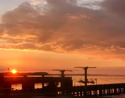a sunset over the ocean with two crosses on a pier at Hvalpsund Færgekro in Hvalpsund