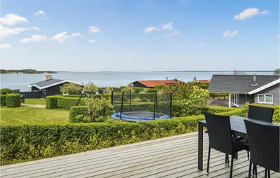 a deck with a table and chairs and a playground at Three-Bedroom Holiday Home In Farso in Farsø