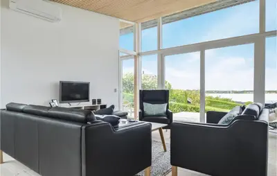 a living room with black leather furniture and large windows at Three-Bedroom Holiday Home In Farso in Farsø