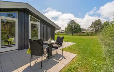 a patio with a table and chairs on a lawn at Four-Bedroom Holiday Home In Fjerritslev in Fjerritslev