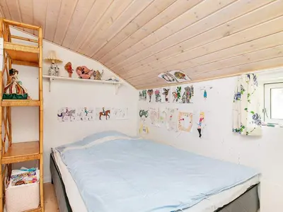 a bed in a room with a wooden ceiling at Holiday Home with Terrace & Fire Pit in Thisted