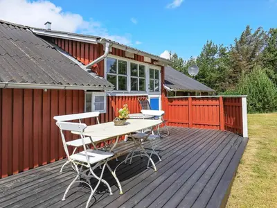 a wooden deck with a table and chairs on it at Holiday Home with Terrace & Fire Pit in Thisted