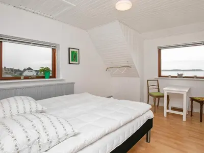 a white bedroom with a bed and a desk and windows at Seaside Retreat in Hvalpsund-By Traum in Farsø