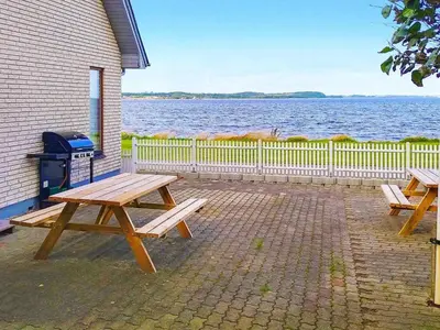 two picnic tables sitting on a brick patio near the water at Seaside Retreat in Hvalpsund-By Traum in Farsø