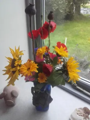 a vase filled with flowers sitting on a window sill at Lindholt in Fjerritslev