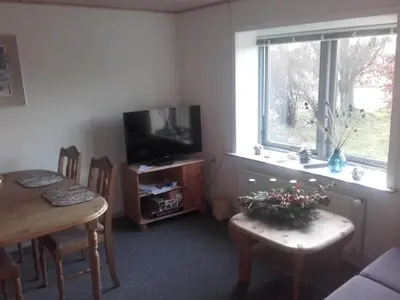 a living room with a table and a television and a table and chairs at Lindholt in Fjerritslev