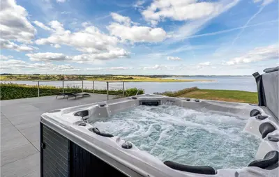 a hot tub on a patio with a view of the water at Amazing Home In Løgstrup With Wifi in Løgstrup
