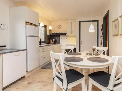 a kitchen and dining room with a white table and chairs at Secluded Forest Retreat-By Traum in Roslev