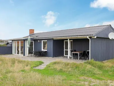 a blue house with a table in front of it at Cozy Coastal Retreat in Vorupor-By Traum in Thisted