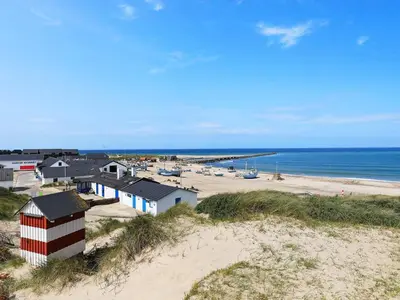 a beach with a red and white building and the ocean at Cozy Coastal Retreat in Vorupor-By Traum in Thisted