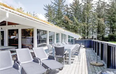 a patio with white chairs and a table on a deck at 4 Bedroom Beautiful Home In Saltum in Saltum