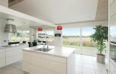 a kitchen with white cabinets and a large window at Beautiful Home In Blokhus With Kitchen in Blokhus