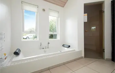 a white bathroom with a tub and two windows at Beautiful Home In Blokhus With Kitchen in Blokhus