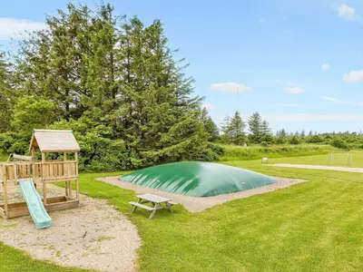 a small green pond with a gazebo and a bench at Vegsø Holiday Park Premium Retreat in Hanstholm