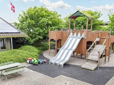 a childrens playground with a slide and benches at Room in Vigsø Holiday Park in Hanstholm
