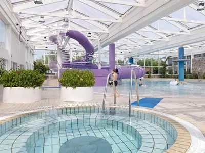a swimming pool with a slide in a building at Room in Vigsø Holiday Park in Hanstholm