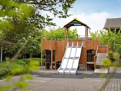 a playground with a slide and a wooden fence at Modern comfort holiday home in Hanstholm