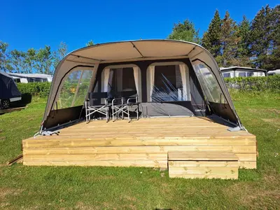 a tent with a wooden deck in a field at Glyngøre Camping in Glyngøre