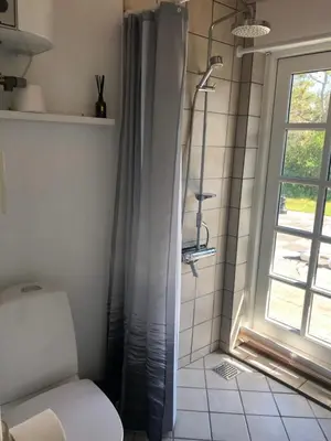 a bathroom with a shower with a toilet and a window at Rødhus Gl. Skole B&B in Pandrup