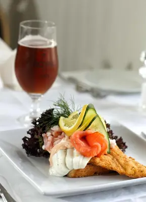 a plate of food with fish and a glass of beer at Aars Hotel in Års