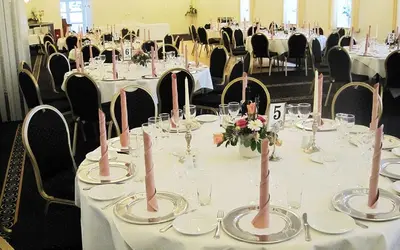 a table with white tables with pink candlesticks on it at Aars Hotel in Års