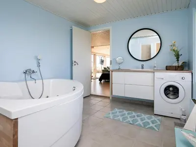 a bathroom with a tub and a washing machine at 6 person holiday home in Løkken in Løkken