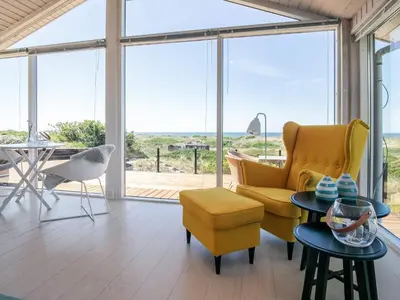 a living room with yellow furniture and a view of the ocean at 6 person holiday home in Løkken in Løkken