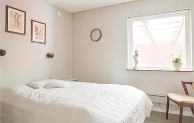 a bedroom with a bed and a clock on the wall at Fjordens Perle in Farsø