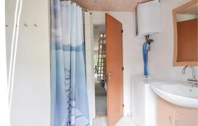 a bathroom with a sink and a shower curtain at Fjordens Perle in Farsø