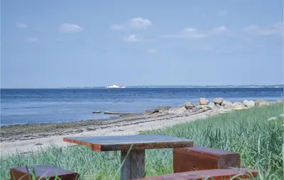 a picnic table sitting on the beach near the water at Fjordens Perle in Farsø