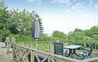 a table and chairs and an umbrella on a deck at Fjordens Perle in Farsø