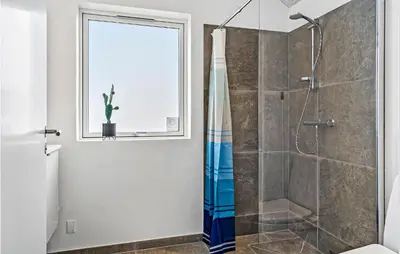 a bathroom with a shower and a window at Nice Home In Harboøre With Sauna in Harboør