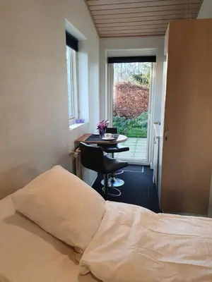 a bedroom with a bed and a table and a window at Bente's Guesthouse in Holstebro