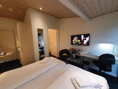 a bedroom with a bed and a desk with chairs at Bente's Guesthouse in Holstebro