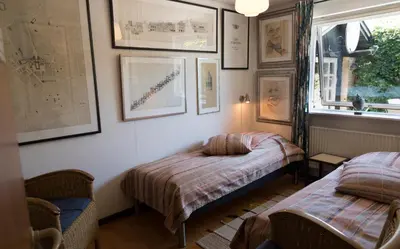two beds in a room with pictures on the wall at Anne Just's Havehotel in Blokhus