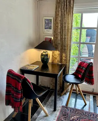 a desk with two chairs and a lamp and a window at Anne Just's Havehotel in Blokhus