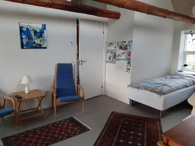a bedroom with a bed and a chair and a table at Brovst bed and breakfast in Brovst