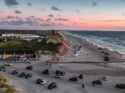 a group of cars parked on the beach at sunset at 6 person holiday home in Blokhus in Blokhus