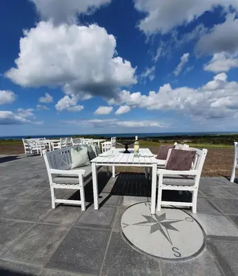 a white table and chairs on a patio with the ocean at Hotel Nor - Badehotellet in Fjerritslev