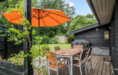 a wooden table and chairs with an orange umbrella at Cozy Home In Hjerm With Kitchen in Hjerm