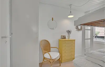 a bedroom with a yellow dresser and a chair at 4 Bedroom Gorgeous Home In Blokhus in Blokhus